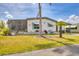 Attractive single-level home with a vibrant lawn, accentuated by a palm tree and a covered carport at 215 Schooner St, North Port, FL 34287