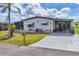 Charming single-story home featuring a well-manicured lawn and a long driveway leading to a covered parking area at 215 Schooner St, North Port, FL 34287