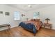 Well-lit bedroom with wood floors, two windows, and unique side table lamps at 25413 Prada Dr, Punta Gorda, FL 33955