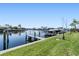 Waterfront dock with multiple boats docked, surrounded by lush green grass, and a clear blue sky at 2645 W Marion Ave # 114, Punta Gorda, FL 33950