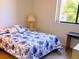 Cozy bedroom with blue floral bedding, lamp, and natural light from the window at 3006 Caring Way # 329, Port Charlotte, FL 33952