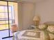Relaxing bedroom showcasing a bed, lamp, and screened balcony access at 3006 Caring Way # 329, Port Charlotte, FL 33952