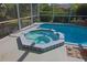 Enclosed pool and hot tub area featuring a tiled hot tub and clear blue water, ideal for relaxation and outdoor enjoyment at 32 Bariloche Dr, Punta Gorda, FL 33983