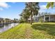 Home with a screened-in lanai, lush lawn, tropical trees, and water views of the canal at 3436 Discovery Dr, Punta Gorda, FL 33983
