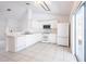 Modern all-white kitchen featuring tile flooring, stainless steel appliances, and access to the lanai through sliding doors at 3436 Discovery Dr, Punta Gorda, FL 33983