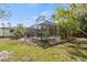 View of the private screened-in pool area from a lush backyard at 3956 Fairchild Ave, North Port, FL 34287