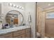 Bathroom with updated vanity, a round mirror, and tiled walk-in shower at 3956 Fairchild Ave, North Port, FL 34287