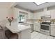 Well-lit kitchen boasts white cabinetry, stainless steel appliances, and a convenient breakfast bar at 3956 Fairchild Ave, North Port, FL 34287