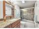 Well-lit bathroom featuring a granite countertop, wood cabinets, and tiled shower with glass doors at 4000 Bal Harbor Blvd # 217, Punta Gorda, FL 33950