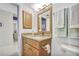 Bathroom with wood cabinets, granite counters, framed mirror and tiled floors; hall visible through door at 4000 Bal Harbor Blvd # 217, Punta Gorda, FL 33950
