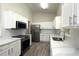 Modern kitchen with stainless steel appliances, white cabinets, and a large sink at 4237 Irdell Ter, North Port, FL 34288
