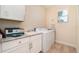 Laundry room with white cabinets, a sink, a washer, a dryer, and a window overlooking a palm tree at 4450 Northshore Dr, Punta Gorda, FL 33980