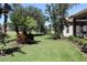 Lush green backyard with well-maintained lawn, mature trees, and landscaping around the home's screened lanai at 629 Misty Pine Dr, Venice, FL 34292