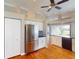 Open-concept kitchen with stainless steel refrigerator, white cabinets, and hardwood floors flowing into the living area at 629 Misty Pine Dr, Venice, FL 34292