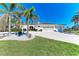 Charming stucco home featuring a tile roof, tropical landscaping, and a large driveway leading to a two-car garage at 740 Via Esplanade, Punta Gorda, FL 33950