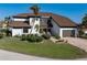 Exterior of a two-story home with manicured lawn, lush landscaping, and a brick driveway leading to a two-car garage at 8 Ocean Dr, Punta Gorda, FL 33950