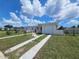 A view of a single-story home featuring a driveway and a well-kept lawn under a partly cloudy blue sky at 858 Conreid Ne Dr, Port Charlotte, FL 33952