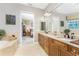 Bathroom featuring dual sinks with wood cabinets, a large mirror and a peek into the main bedroom at 10300 Tarpon Landings Ter # 4, Placida, FL 33946