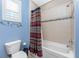 Well-lit bathroom featuring a tub with shower and stylish shower curtain, toilet, and blue accent walls at 10300 Tarpon Landings Ter # 4, Placida, FL 33946
