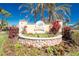 Community entrance sign amidst lush landscaping, featuring decorative stonework and colorful flowerbeds at 10300 Tarpon Landings Ter # 4, Placida, FL 33946