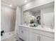 Bright bathroom with double sinks, neutral tiling, and a glass door shower with a large mirror at 12141 Karney Ave, Port Charlotte, FL 33981