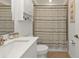 Bathroom with white vanity, toilet, beige shower curtain, and warm beige wall tiles for a cozy feel at 1353 Newton St, Port Charlotte, FL 33952