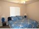 Cozy bedroom with a ceiling fan, large window, and a bed featuring a blue patterned comforter at 1500 Westover St, Port Charlotte, FL 33953