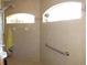 Bright bathroom shower with a showerhead, neutral tiling, windows and a grab bar at 1500 Westover St, Port Charlotte, FL 33953
