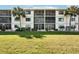 Three-story condo building featuring screened balconies, well-maintained landscaping, and lush green lawn at 175 Kings Hwy # 717, Punta Gorda, FL 33983