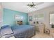 Comfortable bedroom with blue accent wall, ceiling fan, neutral tile flooring, and bright window at 196 The Corso # 196, Venice, FL 34285