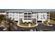 Three-story condo building featuring a light blue facade, a metal roof, and well-manicured landscaping at 2001 Bal Harbor Blvd # 2202, Punta Gorda, FL 33950