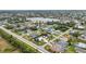 Wide aerial view of a neighborhood with varying home styles, screened pools, and a picturesque lake in the background at 23531 Dunstan Ave, Port Charlotte, FL 33954