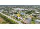 An aerial view of a quiet neighborhood showcasing a home with a lush green lawn, mature trees and nearby lake at 23531 Dunstan Ave, Port Charlotte, FL 33954