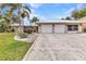 Charming single-story home featuring a two-car garage, landscaped yard, and tropical palm trees at 23531 Dunstan Ave, Port Charlotte, FL 33954