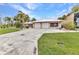 Charming single-story home featuring a two-car garage, landscaped yard, and tropical palm trees at 23531 Dunstan Ave, Port Charlotte, FL 33954