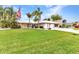 Beautiful front yard with green lawn, palm trees, landscaping, and an American flag flying proudly at 23531 Dunstan Ave, Port Charlotte, FL 33954