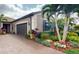 Charming home featuring a paver driveway, two-car garage, and tropical landscaping at 2436 Arugula Dr, North Port, FL 34289
