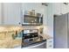 Close-up of a modern kitchen highlighting stainless steel appliances, granite countertops, and tile backsplash at 2810 Sherman Oak Dr, North Port, FL 34289