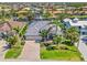 Aerial view of a waterfront home with a backyard canal, lush landscaping, and a large driveway at 3812 Carupano Ct, Punta Gorda, FL 33950