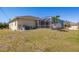 The rear exterior of the home features a screened-in pool area, surrounded by a spacious lawn at 7014 Baylor Street, Englewood, FL 34224