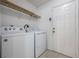 Functional laundry room with a washer, dryer, tile floor and storage shelves at 7014 Baylor Street, Englewood, FL 34224