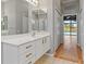 Bathroom featuring double sinks with modern white cabinetry, hallway access and a pool view at 8774 Mystic Cir, North Port, FL 34287