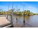 View of a boat lift on the canal, with stairs, set against a clear blue sky and lush greenery at 8774 Mystic Cir, North Port, FL 34287