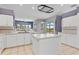 Bright kitchen features white cabinetry and center island with view of backyard at 8774 Mystic Cir, North Port, FL 34287