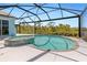 A screened-in pool and spa area with a clear view of the water, surrounded by lush landscaping at 8774 Mystic Cir, North Port, FL 34287