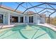 Inviting pool and spa area beneath a screened enclosure, complemented by the home's blue exterior at 8774 Mystic Cir, North Port, FL 34287