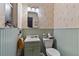 Small bathroom with light-green wainscoting, patterned wallpaper and compact fixtures at 1060 Venetian Pkwy, Venice, FL 34285