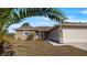 Inviting single-story home with a red front door and lush landscaping at 121 Long Meadow Ln, Rotonda West, FL 33947