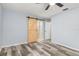 Bedroom with wood-look flooring, fresh paint, and a rustic sliding barn door to ensuite bath at 1341 Preston St, Port Charlotte, FL 33952