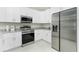 Modern kitchen with stainless steel appliances, white cabinets, and light granite countertops at 1384 Alpinia Rd, North Port, FL 34288